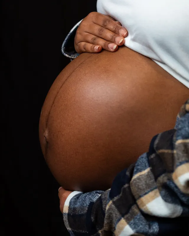 A pregnant belly held gently by loved ones